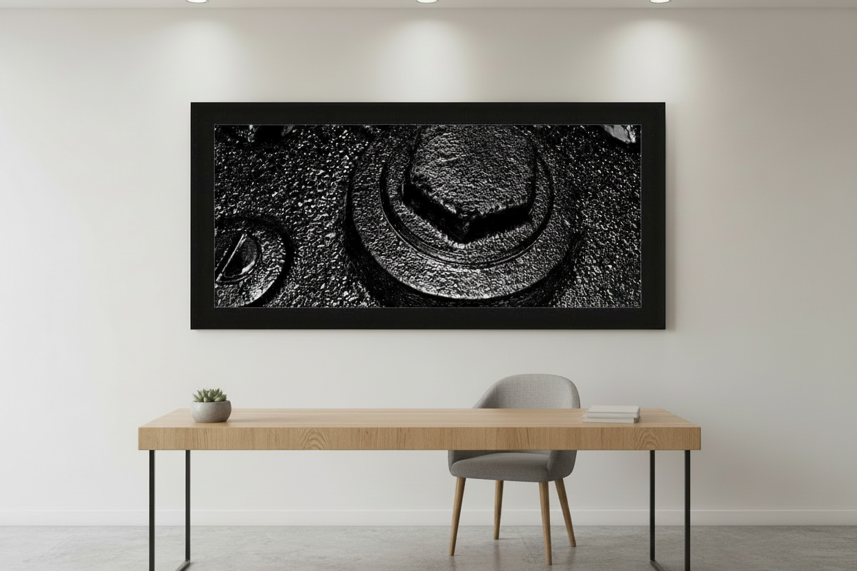 Black and white abstract wall art print in modern frame above minimalist desk, featuring textured industrial design.