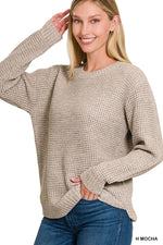 Woman wearing a beige sweater and blue jeans on a white background