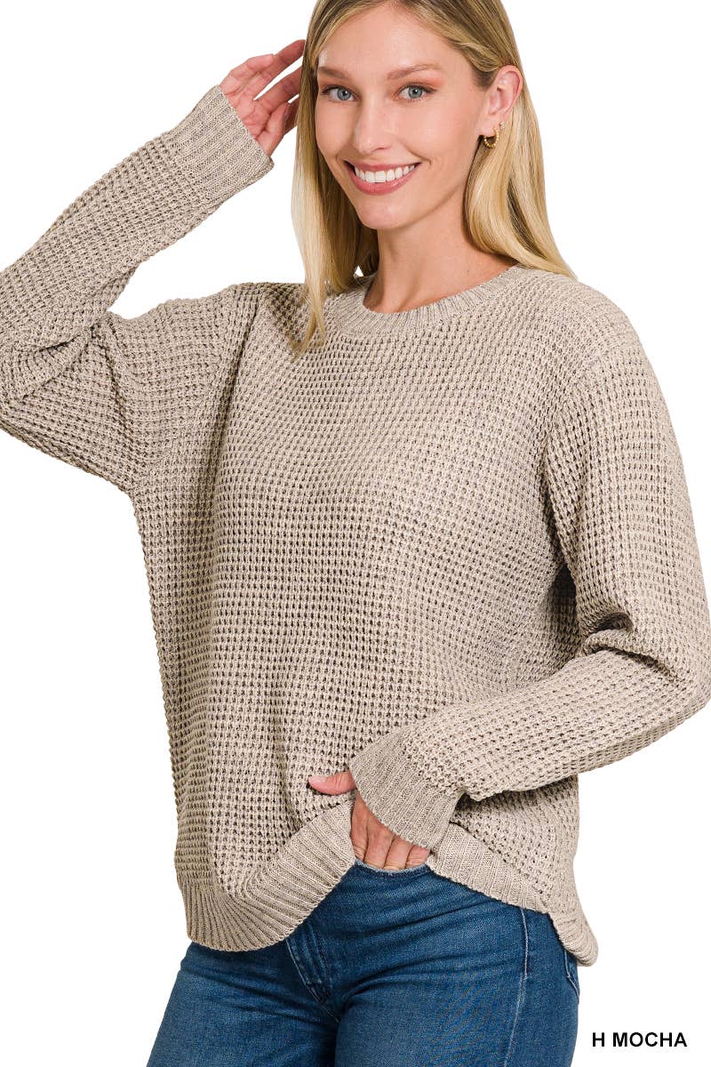 Woman wearing a beige sweater and blue jeans on a white background