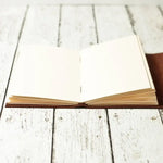 Open blank journal on white rustic wood table, ideal for writing or sketching