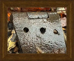 Rusty metal hinge with three holes, nestled in autumn leaves, framed in wood