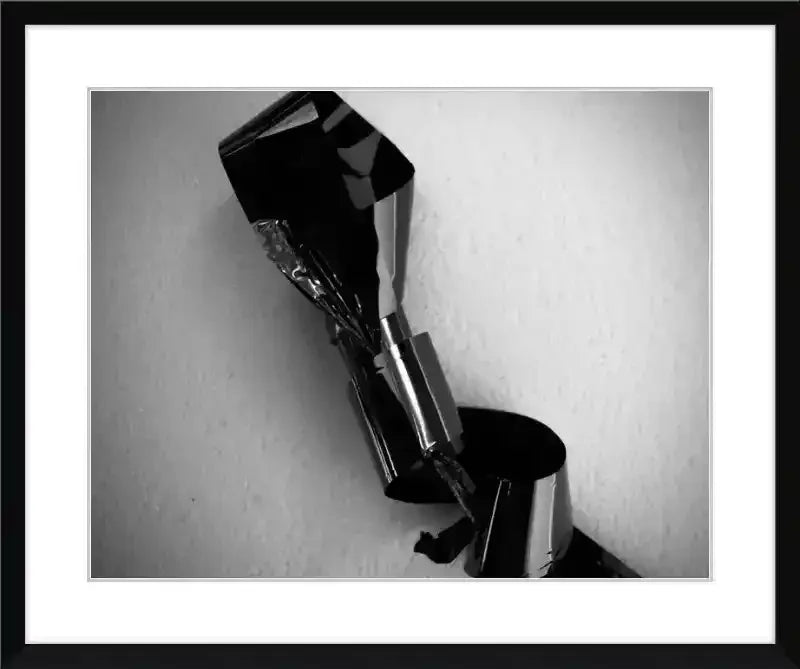 Black and white framed print of abstract metallic sculpture against textured wall