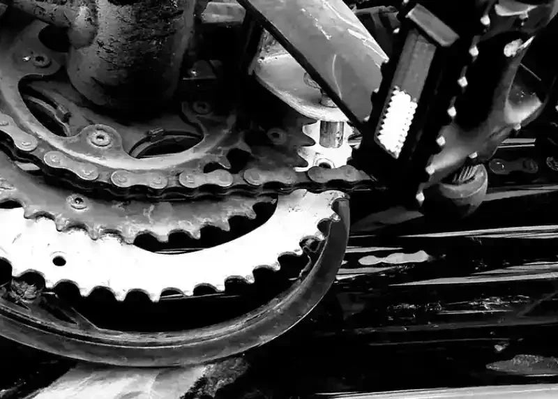 Black and white close-up of vintage bicycle gears and chain, showcasing mechanical details and texture