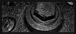 Black and white textured close-up of a hex bolt and washer on rough metal surface