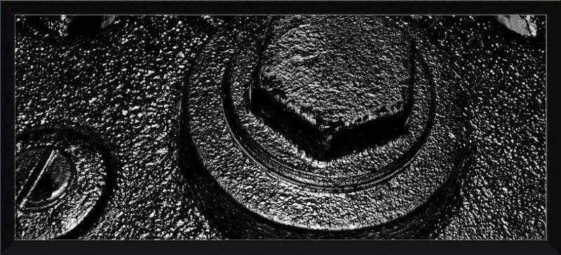 Black and white textured close-up of a hex bolt and washer on rough metal surface