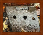 Rusty metal hinge with three holes, nestled among autumn leaves, framed in wood