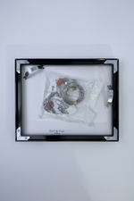 Packaged hanging kit in a clear plastic bag with a black frame.