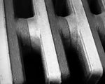 Black and white close-up of textured cast iron radiator fins, showcasing industrial detail and shadow contrast.