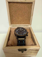 Wooden watch box with a black wristwatch on a white background