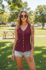 Woman wearing a maroon sleeveless button-up top and denim shorts outdoors.