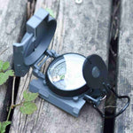 Compass on a wooden surface with greenery