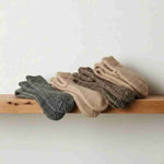Set of four pairs of socks in gray, beige, and brown on a wooden surface with a light background.