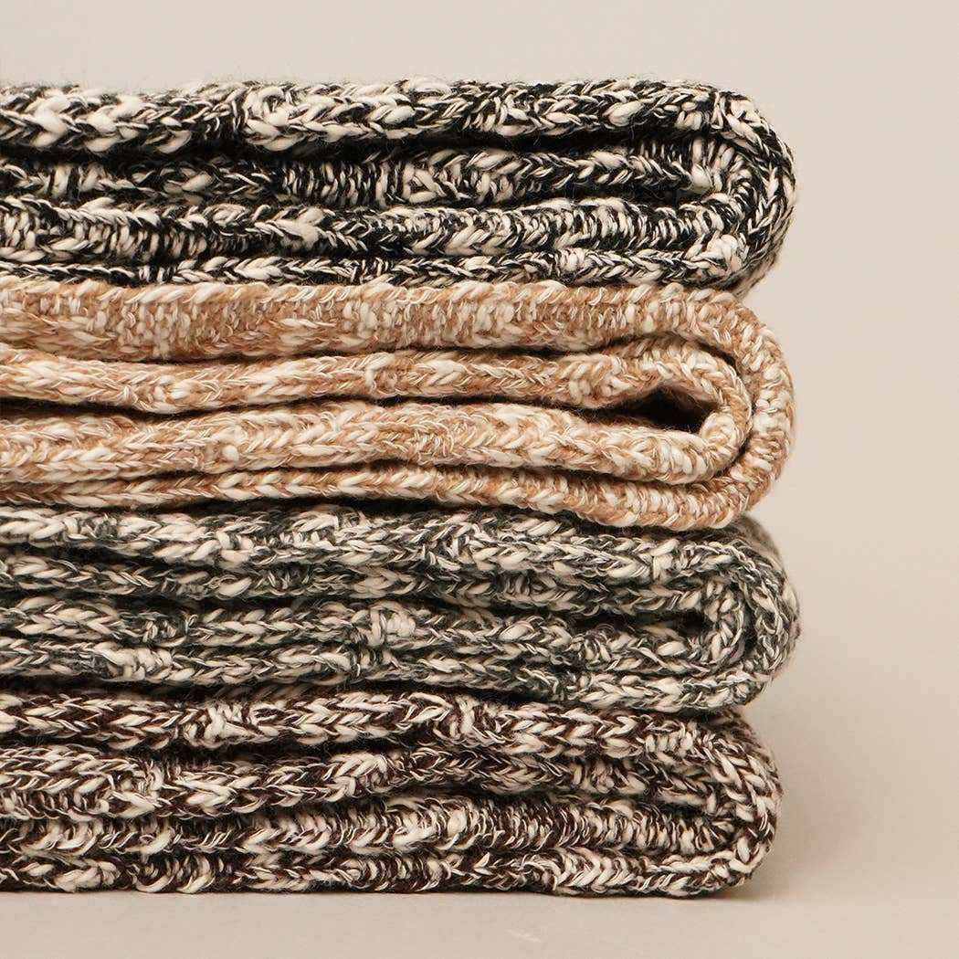 Stack of folded textured blankets on a neutral background