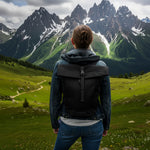 Woman with backpack admiring snow-capped mountains in green alpine meadow, wildflowers, cloudy sky