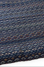 Close-up of a woven fabric with a blue and multicolor pattern on a plain background