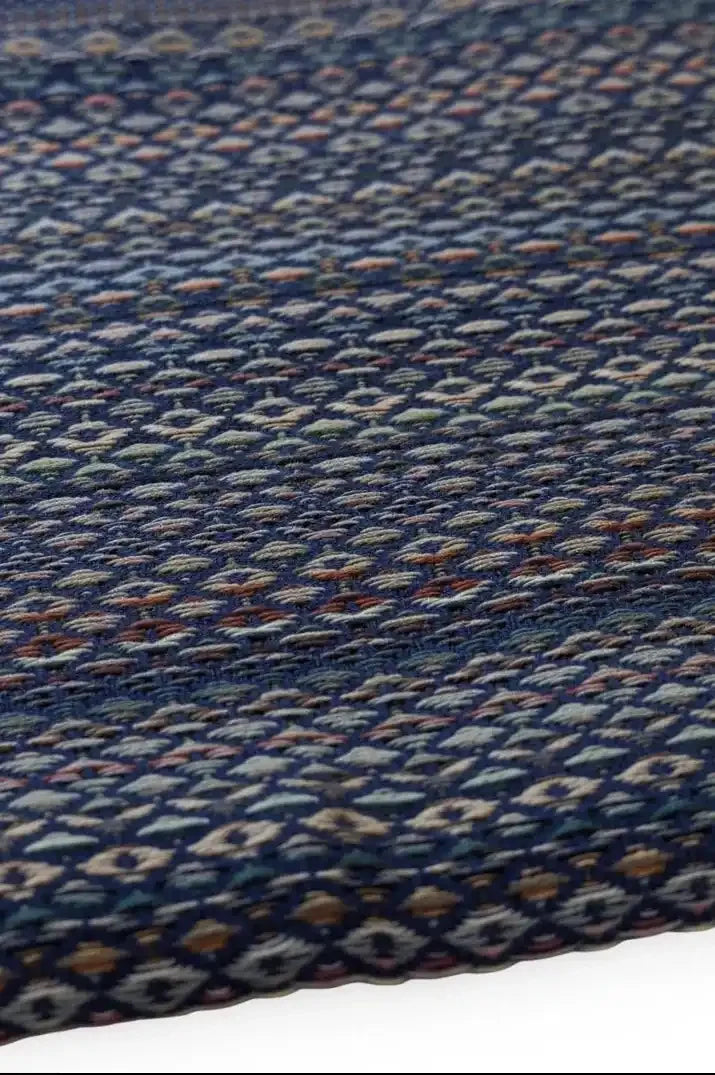 Close-up of a woven fabric with a blue and multicolor pattern on a plain background