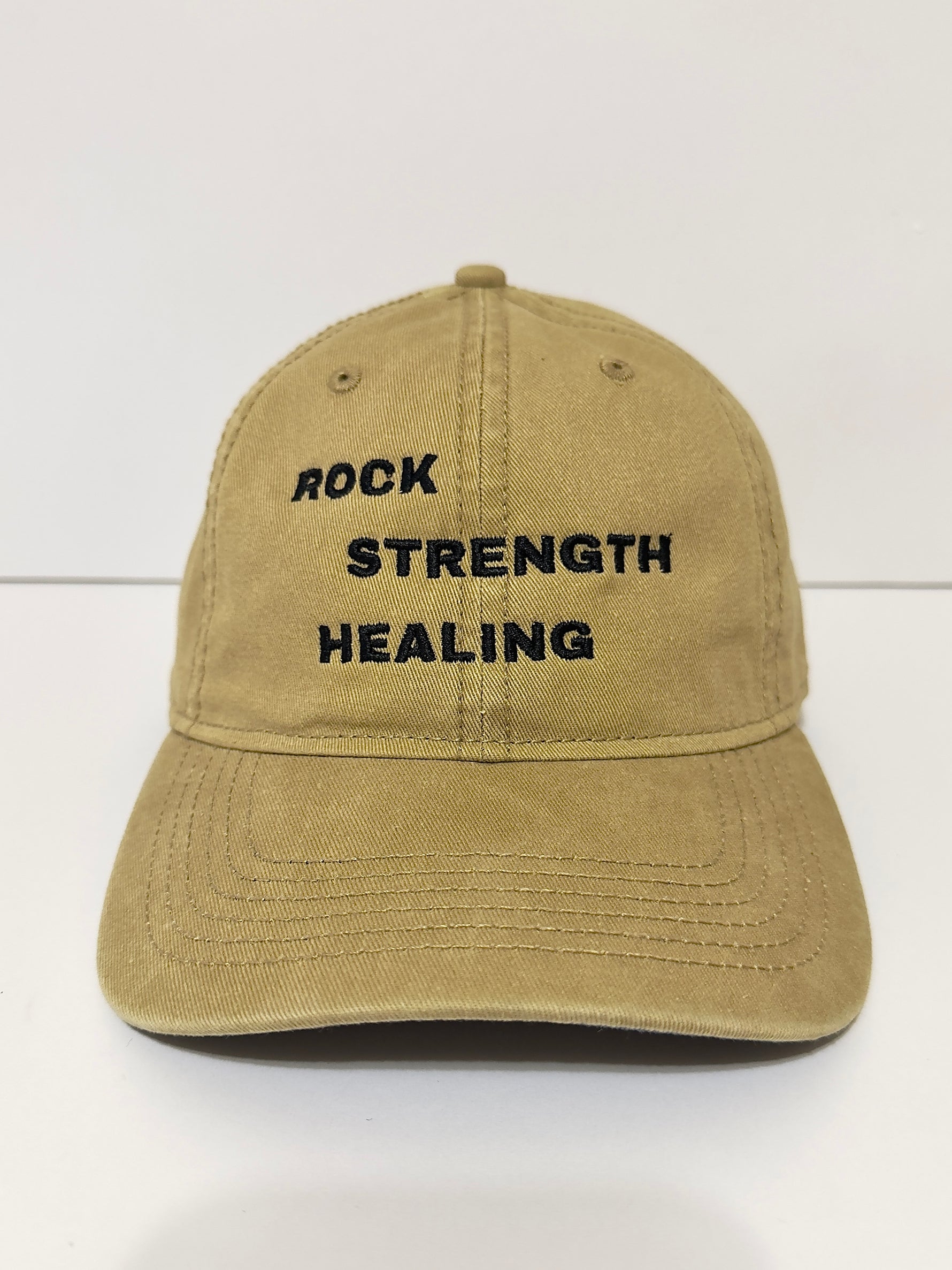 Beige cap with 'Rock Strength Healing' text on a white background