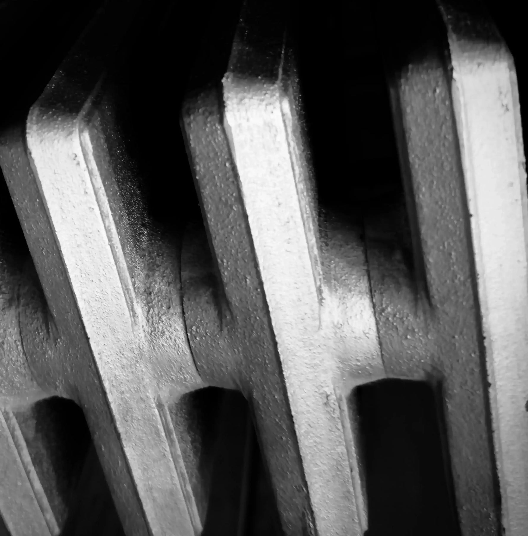 Black and white close-up of textured metal gear teeth, industrial photography print