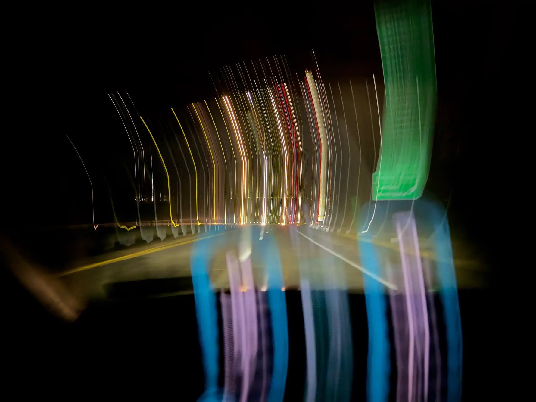 Long exposure night road with streaking car lights and green highway sign, abstract motion blur
