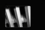 Close-up of textured metal grate with geometric shadows, monochrome industrial photography