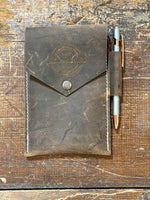 Distressed leather notebook cover with pen holder, rustic wood background