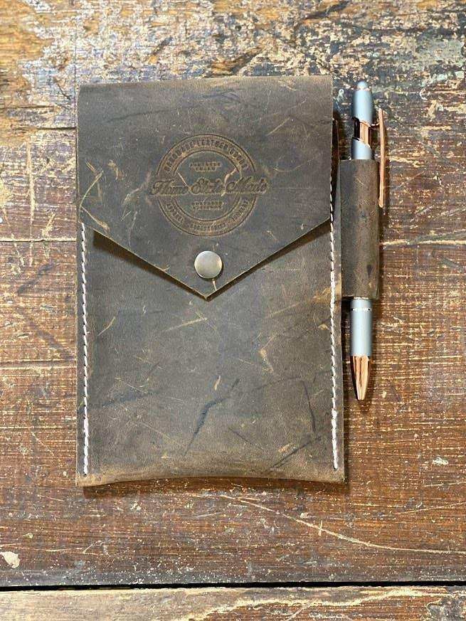 Distressed leather notebook cover with pen holder, rustic wood background