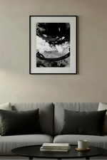 Black and white framed print of abstract mechanical gear above modern gray sofa in minimalist living room