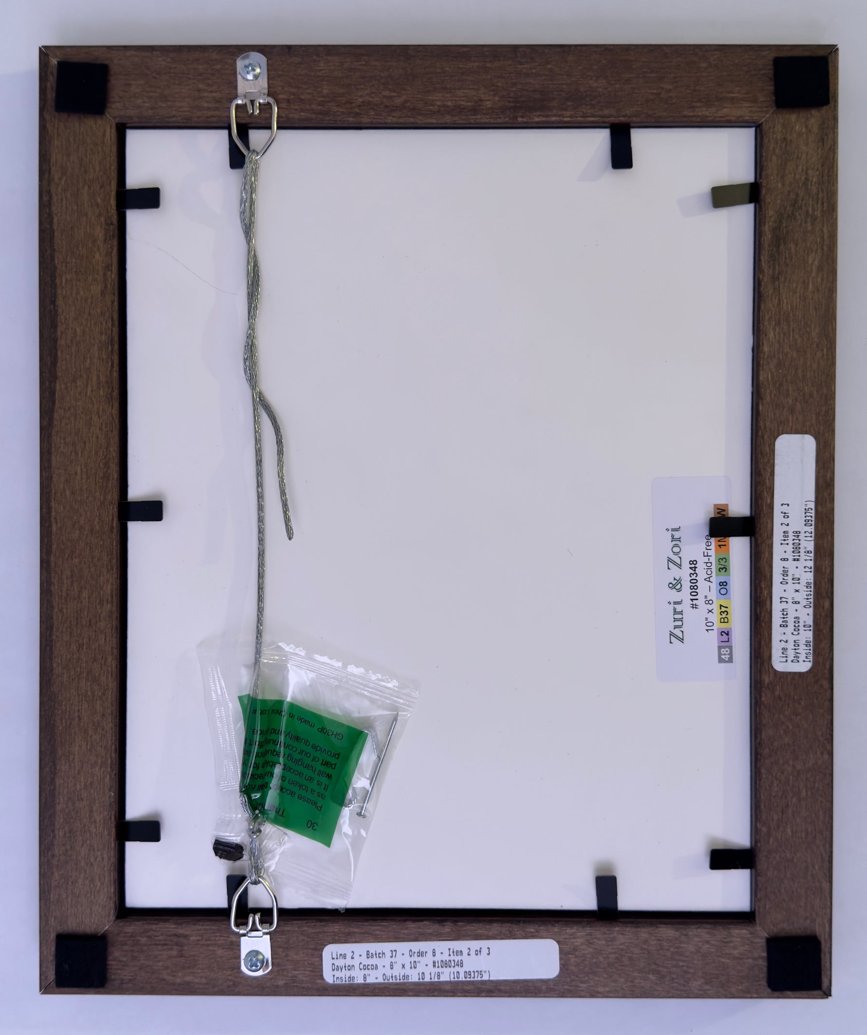 Back of a framed picture with hanging hardware and label