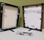 Two picture frames with hardware on a white surface against a green wall.