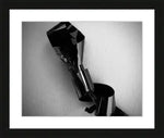 Black and white abstract photography print in black frame, featuring metallic sculpture against textured wall