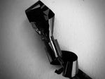 Shiny black and chrome abstract sculpture against textured white wall