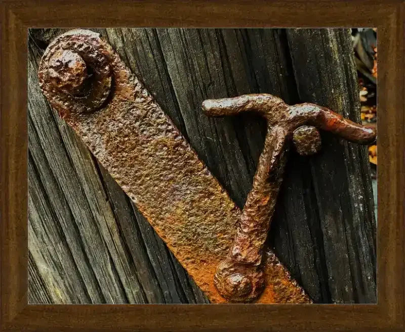 Rusty antique metal latch on weathered wood, framed print with rustic texture and vintage charm