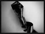 Black and white abstract photo of twisted metallic object against textured wall, framed print