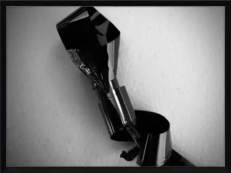 Black and white abstract photo of twisted metallic object against textured wall, framed print
