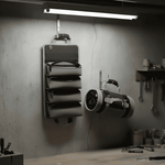 Wall-mounted tool organizer in a workshop setting with tools on the wall and table.