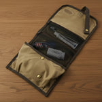 Tan and gray travel organizer with mesh pockets holding toiletries on wooden surface