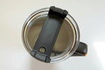 Top view of stainless steel travel mug with black lid and handle, showing interior and sip opening