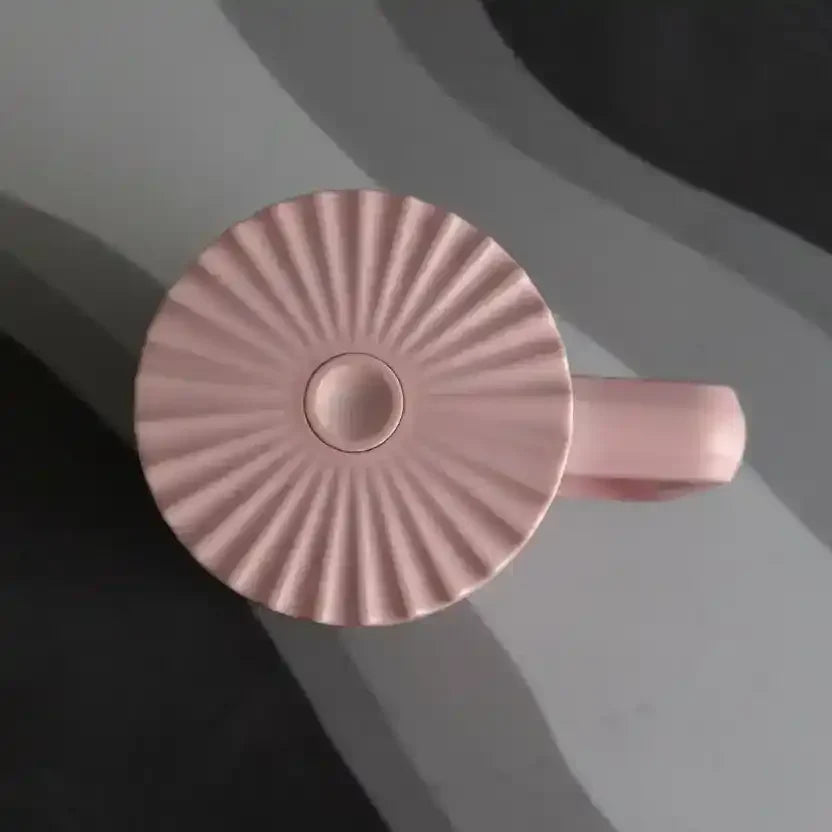 Pink fluted ceramic mug with handle, minimalist design on gray background