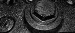 Close-up of textured metal surface with bolts, black and white industrial detail
