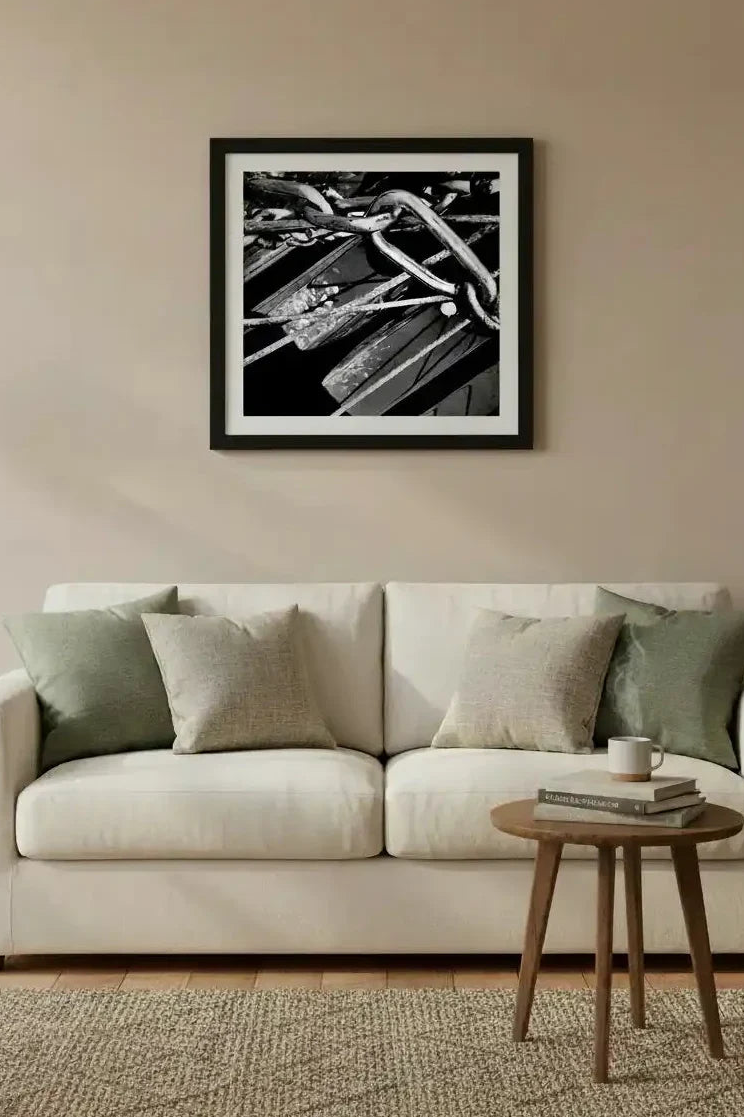Black and white framed print of intertwined metal chains above a modern sofa in a cozy living room.