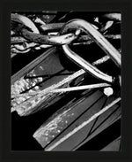 Black and white framed print of intertwined metal chains and rustic hardware, showcasing industrial textures and shadows.