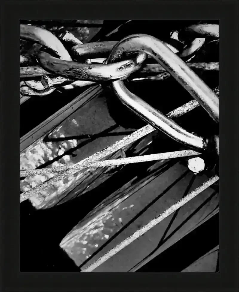 Black and white framed print of intertwined metal chains and rustic hardware, showcasing industrial textures and shadows.