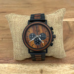 Wooden watch with black accents on a textured pillow against a wooden background