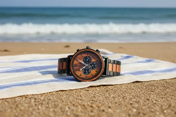 Wooden watch with chronograph face on striped beach towel by ocean waves