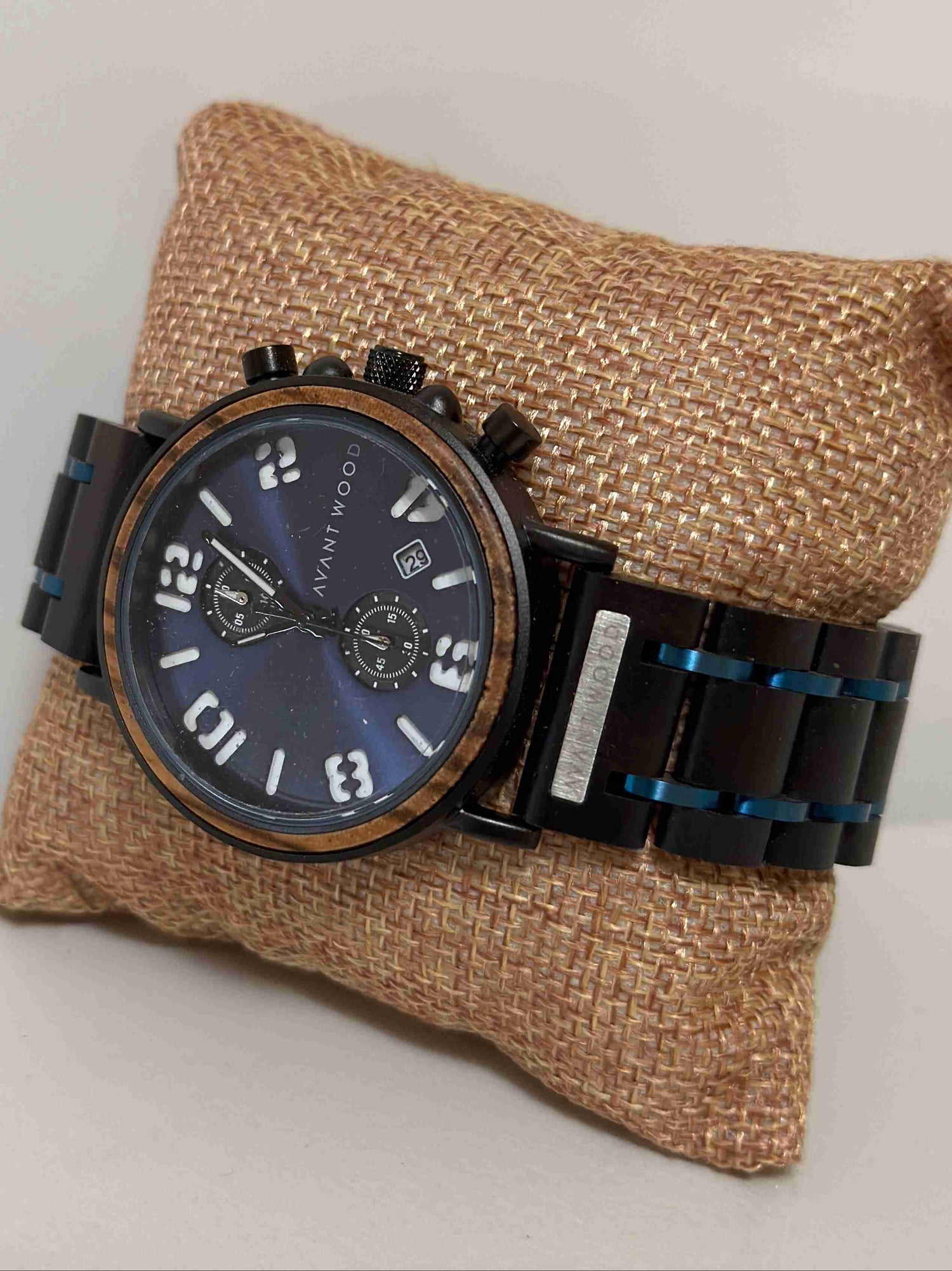 Watch with black strap and blue face on a textured brown pillow