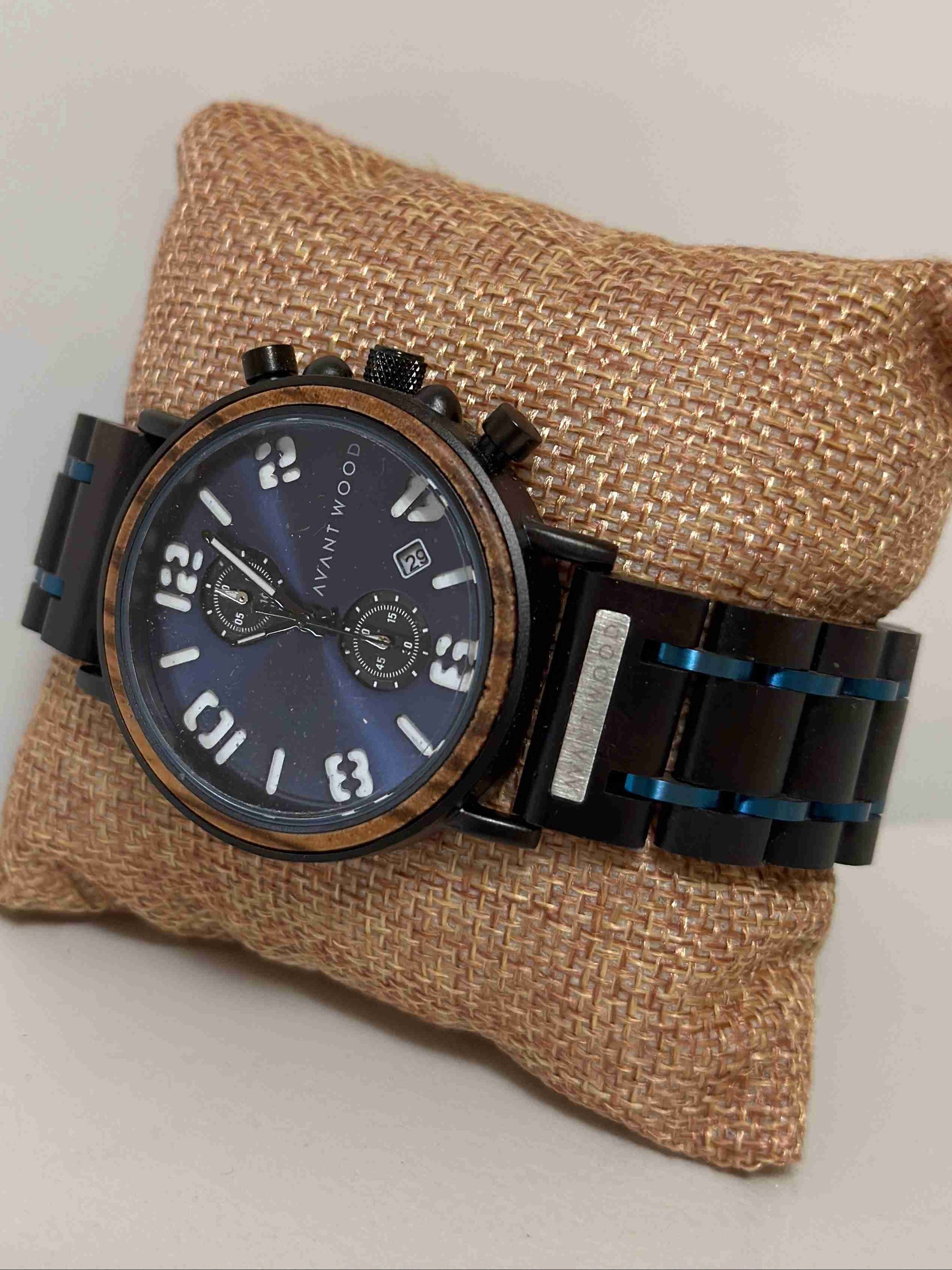 Watch with black strap and blue face on a textured brown pillow