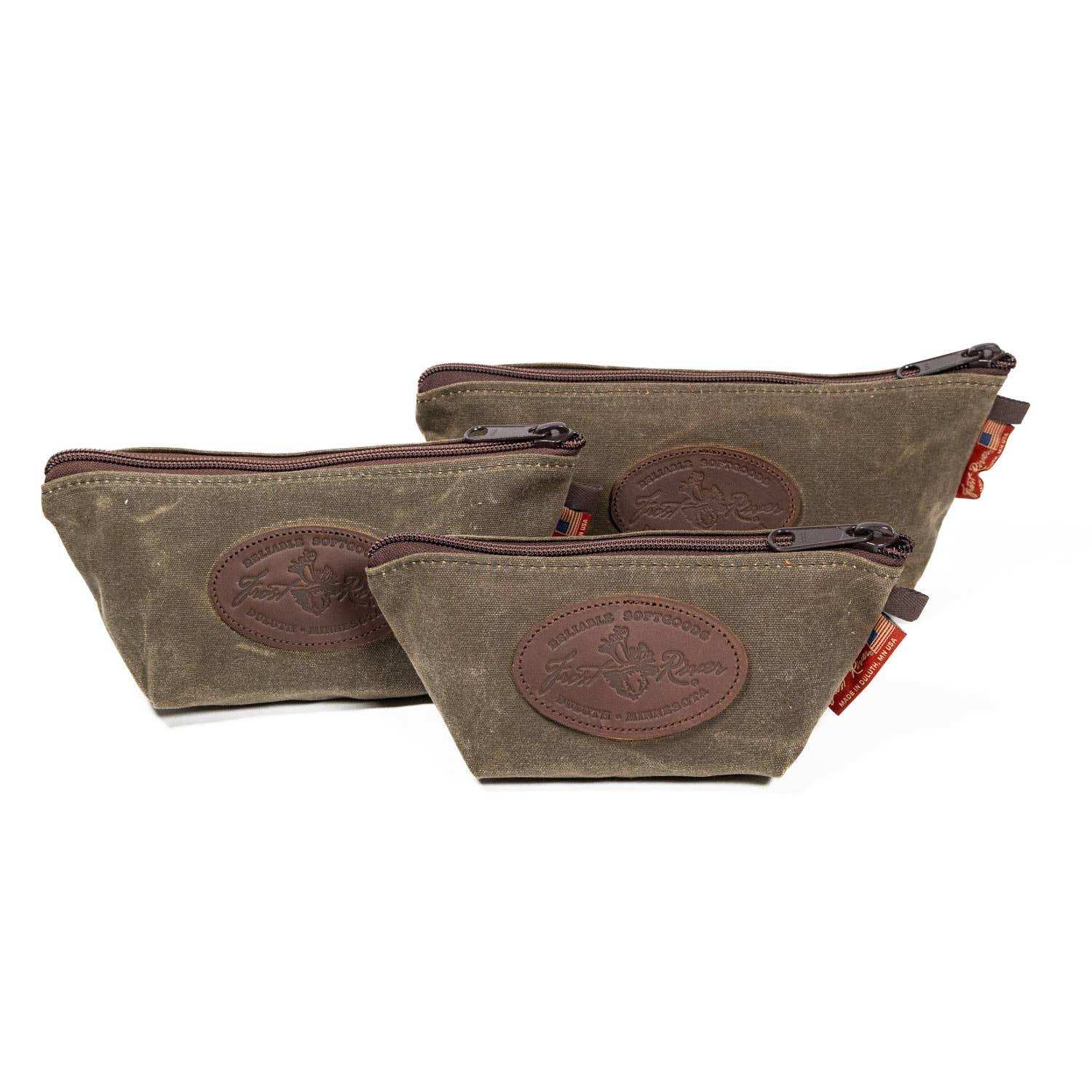 Three brown waxed canvas pouches with leather patches on a white background