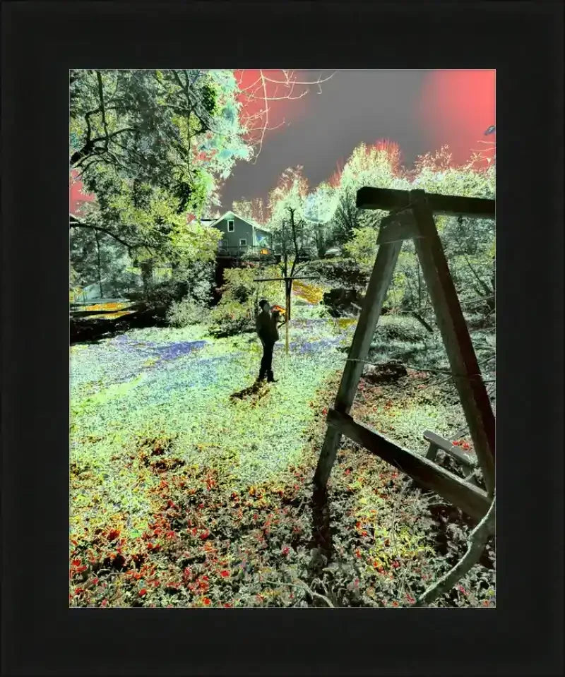 Framed surreal garden print with vibrant colors, wooden swing, and figure under red sky