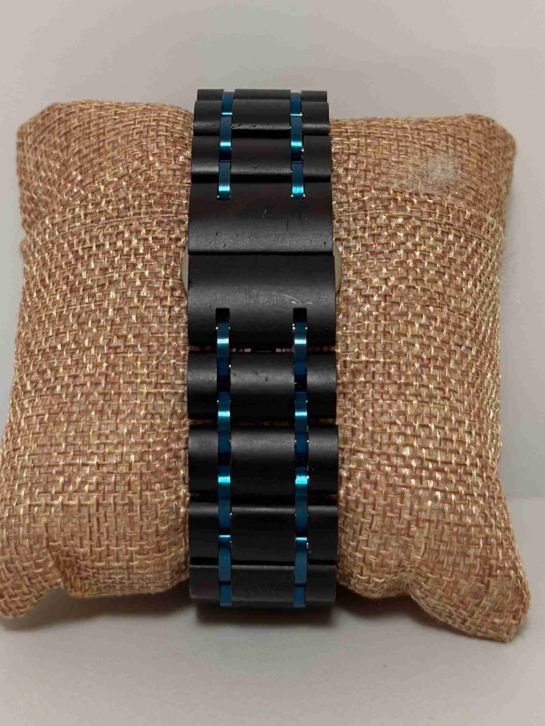 Black metal bracelet with blue accents on a textured brown surface
