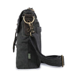 side view of black canvas crossbody bag with brass hardware on a white background